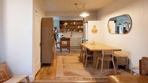 A cozy living room with a wooden floor, a sofa, a dining table with chairs, and a kitchen in the background. - Short North, Free Parking, Italian Village (Columbus)