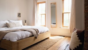 A bedroom with a large bed, a wooden floor, and two windows with curtains. - Short North, Free Parking, Italian Village (Columbus)