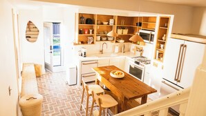 A compact kitchen with a wooden table, stools, and built-in shelves. - Short North, Free Parking, Italian Village (Columbus)