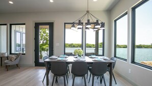 A dining area with a table set for four, large windows, and a view of a lake. - City Escape - Lakefront + Dock + Firepit + Fishing (Kingsland)