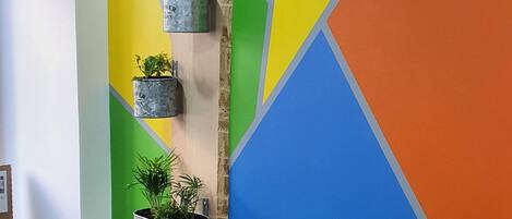 A room with a colorful geometric wall design, a wooden floor, and metal planters with plants.