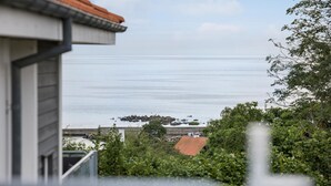 Une vue sur la côte, avec un ciel dégagé, une étendue d’eau et une ligne de rivage lointaine parsemée de bâtiments.