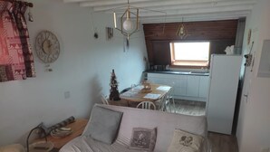 Un salón acogedor con sofá, una mesa de comedor y una cocina al fondo.