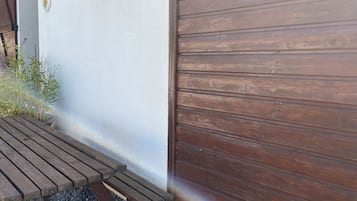 A wooden deck with a gravel path, a metal gate, and a potted plant with red flowers.