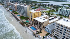 Un hotel costero con varias edificaciones, una playa y una extensa masa de agua al fondo.