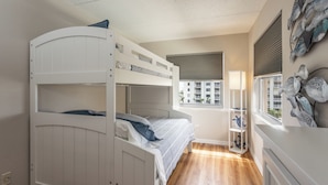 Habitación con literas, una ventana, una lámpara y un adorno en la pared.