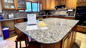 A kitchen with wooden cabinets, a granite countertop, a welcome sign, and a window with a view. - Serene Escape in West Sedona w/ Gorgeous Views (Sedona)
