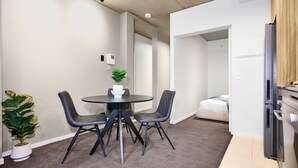 A modern kitchen with a refrigerator, a sink, and a countertop. There is a dining area with a table and chairs. - Melbourne CBD Stay - Balcony, Gym & Prime City Location (Melbourne)