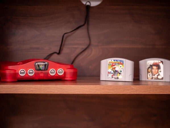 A Nintendo Wii console connected to two game cartridges on a wooden shelf.