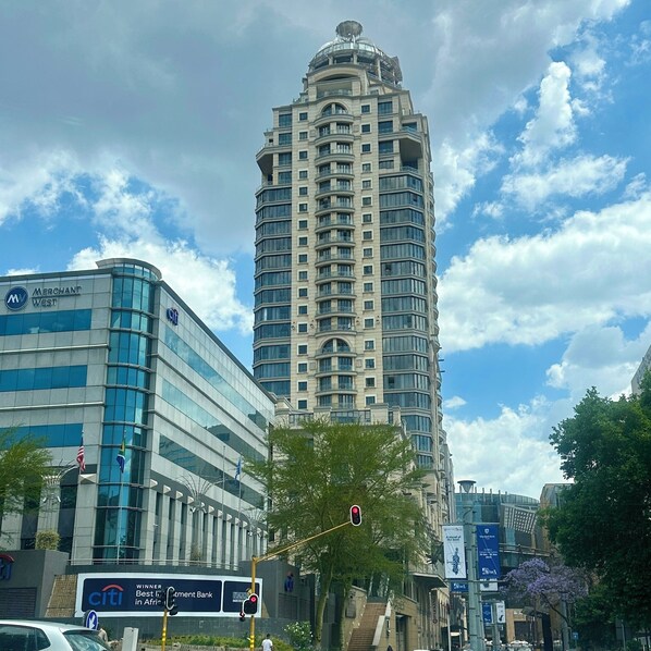 A tall, modern building with a curved facade and multiple balconies.