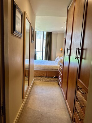 A hotel room with a bed, a dresser, a mirror, and a window with curtains.