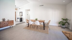 A modern dining area with a wooden table, white chairs, and a woven rug. - Charming 3-bedroom house with WiFi and AC in wonderful Las Vegas (Las Vegas)