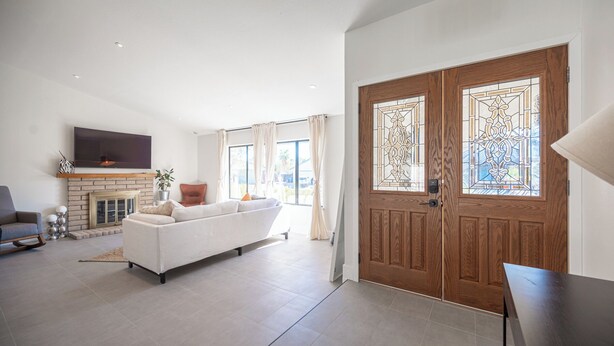 A spacious living room with a white sofa, a fireplace, and a large wooden door with stained glass panels. - Charming 3-bedroom house with WiFi and AC in wonderful Las Vegas (Las Vegas)