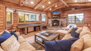 A log cabin interior with a stone fireplace, a pool table, and a cozy seating area. - Buffalo Lodge|Hot Tub, EV Charge, Gated, By Slopes (Big Bear)