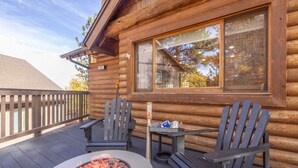 A log cabin with a deck featuring two Adirondack chairs, a fire pit, and a small table with snacks. - Buffalo Lodge|Hot Tub, EV Charge, Gated, By Slopes (Big Bear)