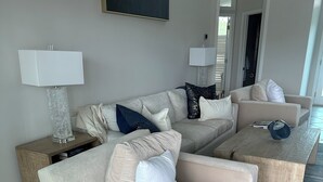 Uma sala de estar com sofá seccional, mesa de centro e abajur em mesa lateral.