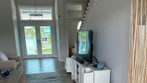 Uma sala de estar ampla com uma televisão grande, um sofá, uma mesa de centro e uma escada que dá para outro andar.