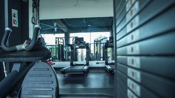 Une salle de sport équipée de matériel d’exercice, d’un tapis de course et de supports pour les poids.