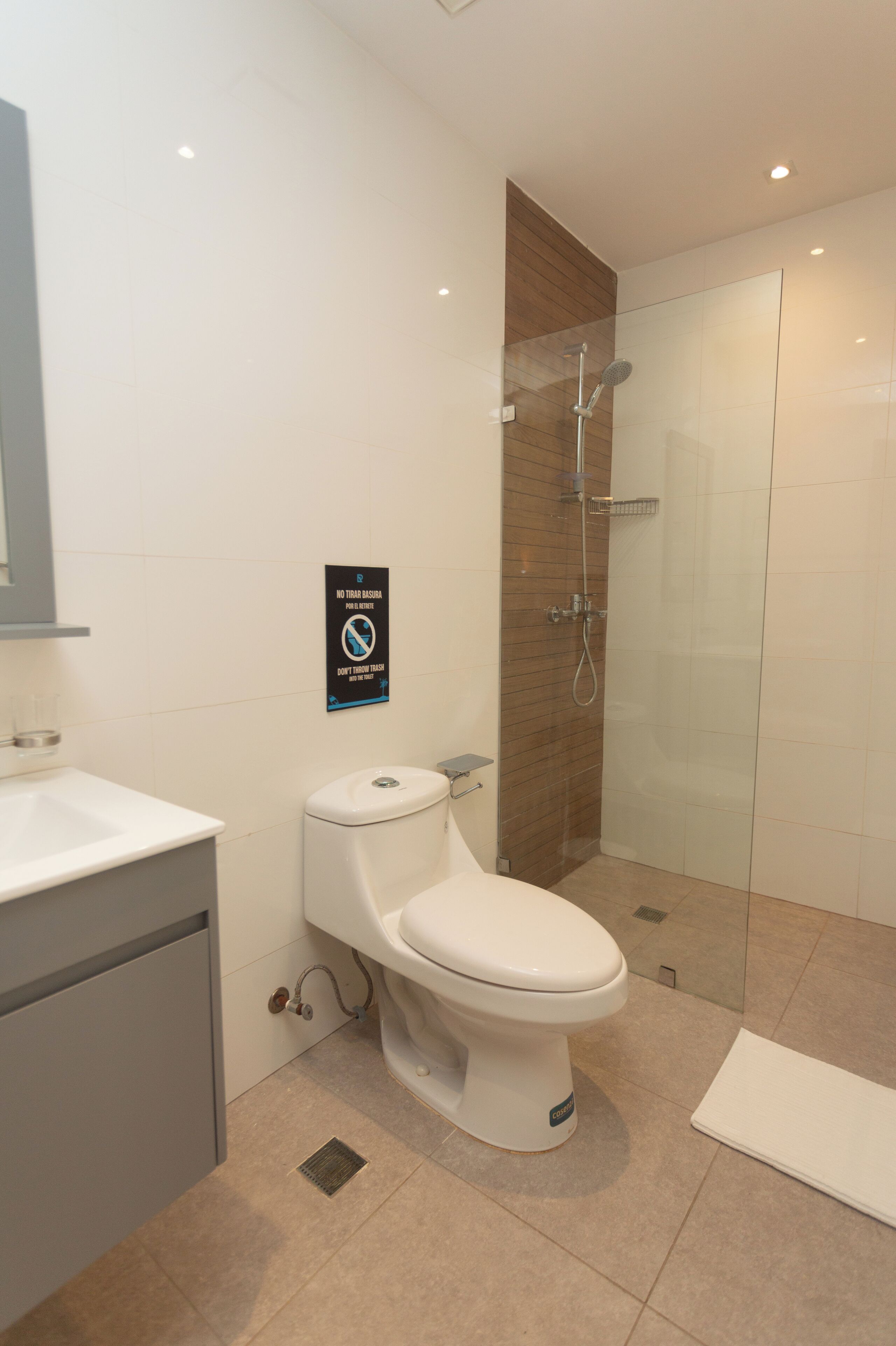 Et moderne badeværelse med toilet, glasbrusekabine og håndvask.