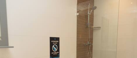 A modern bathroom with a toilet, a glass shower enclosure, and a sink.