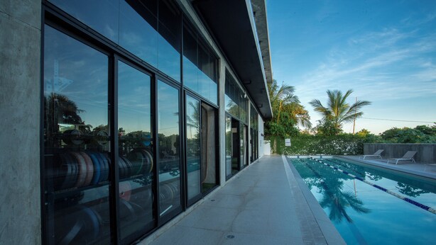 A modern building with large glass windows reflecting palm trees and a clear sky. - Las Golondrinas Cabarete (Cabarete)