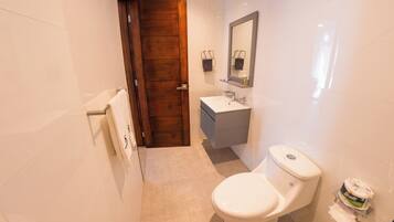 Un baño moderno con puerta de madera, lavamanos blanco y un inodoro.