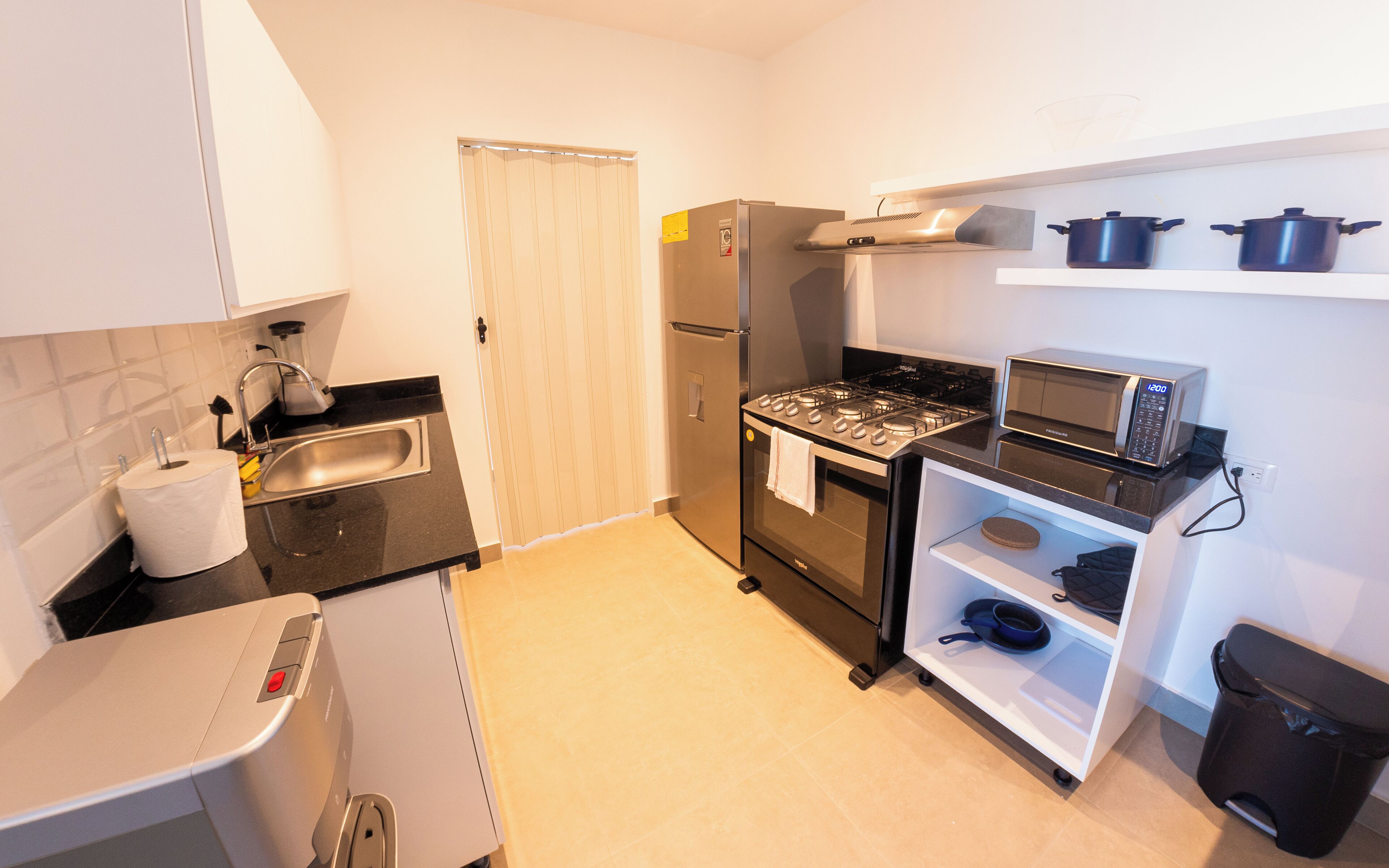 A compact kitchen with a refrigerator, stove, microwave, and a small sink.