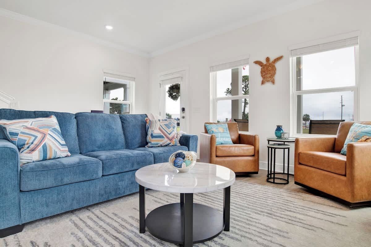 {LIVING ROOM} Offers enough seating, an open floor plan, and natural light with bay views. Enjoy a 55" smart TV for entertainment and a selection of board games for fun gatherings. Best for relaxing or spending quality time with family and friends.