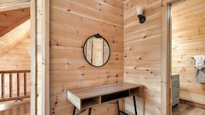 Un intérieur en bois avec un bureau en bois, un miroir et un petit meuble.