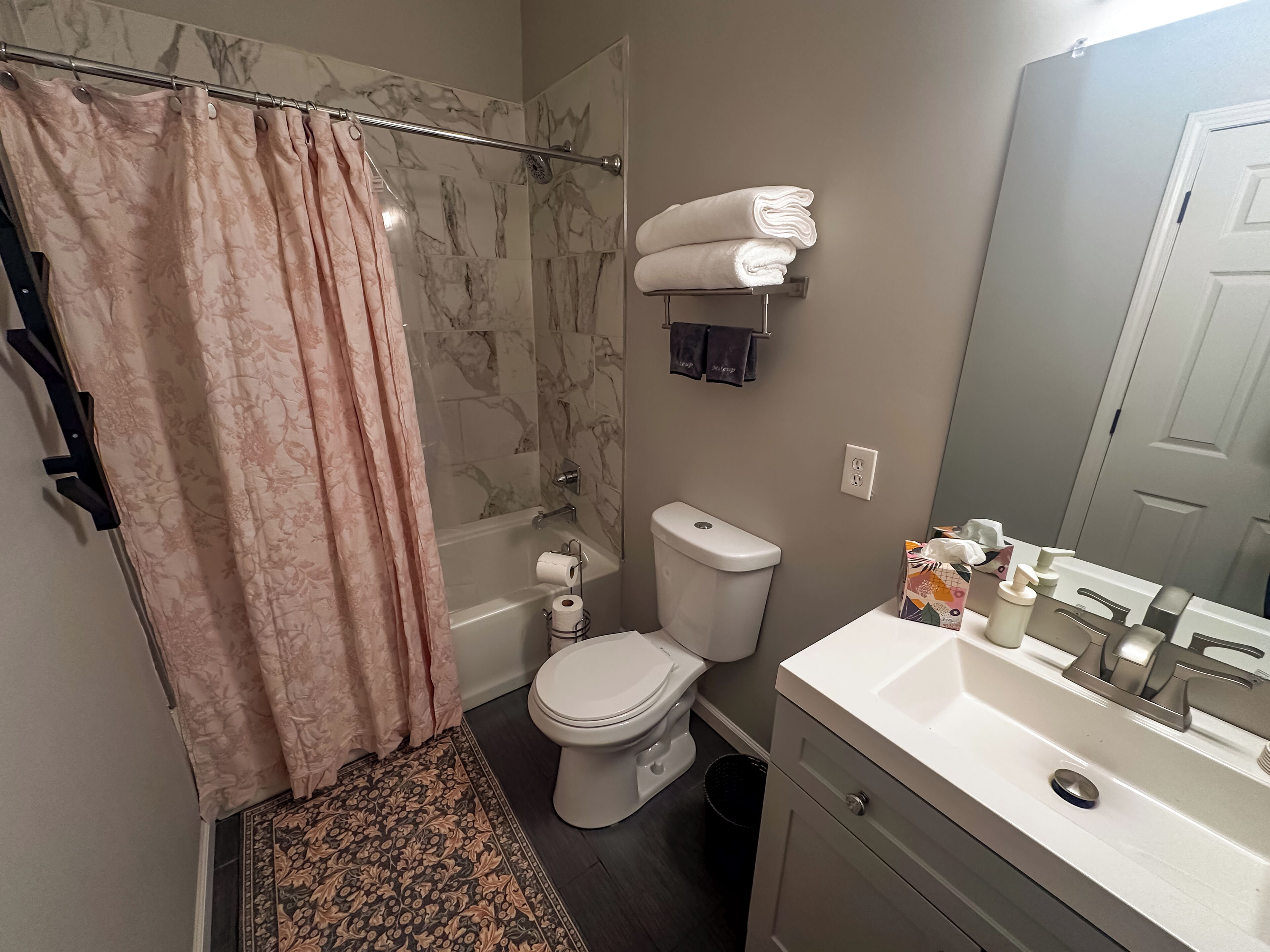 Un baño con cortina de ducha, inodoro, lavabo y toallero.