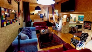 Una sala de estar acogedora con un sofá, sillones, una mesita de centro y un televisor.