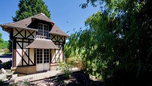 Una casa tradicional de entramado de madera con un porche de madera y un pequeño jardín.