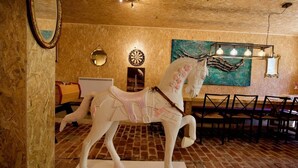 Una habitación con una escultura de un caballo blanco, un dardo, un cuadro y un comedor con sillas y una mesa.