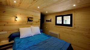 Una habitación de cabaña de madera con una cama, un cuadro colgado y una ventana.