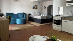 A modern living room with a sofa, a bed, a kitchen area, and a dining table. - Villa Sedef (Neum)