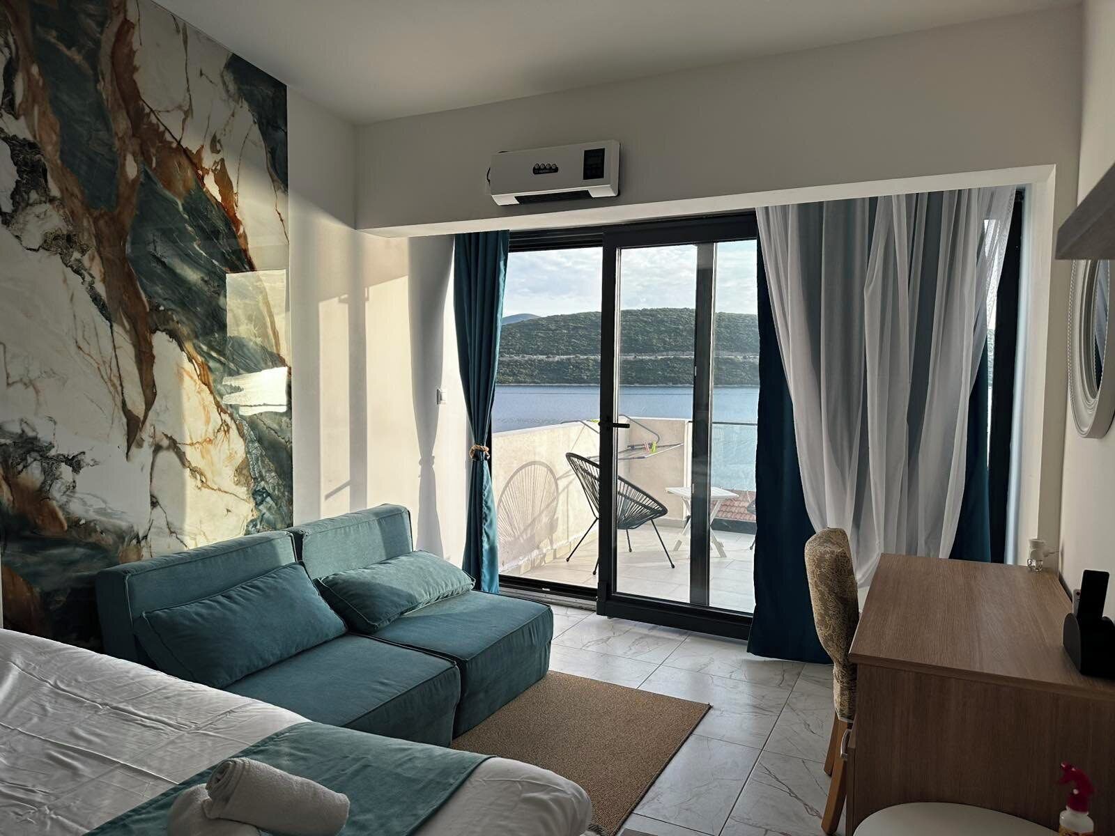 Ein Hotelzimmer mit einer Couch, einem Bett, einem Schreibtisch und Blick auf ein Gewässer.