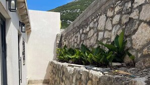 A narrow pathway leading to a white building with a stone wall on one side. - Villa Sedef (Neum)