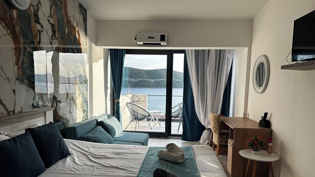 A hotel room with a bed, a desk, a chair, a TV, and a view of the sea. - Villa Sedef (Neum)