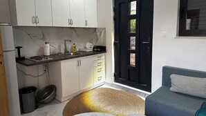 A compact kitchen with white cabinets, a black door, a marble countertop, and a round table. - Villa Sedef (Neum)