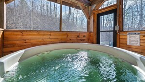 A wooden cabin with a hot tub and large windows. - Log Cabin Amazing Location - Private - Cozy 3-bedroom Sleeps 8 - Hot Tub (Sevierville)