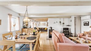 Una sala acogedora con chimenea, un comedor con muebles de madera y un sofá con un cojín rosa.