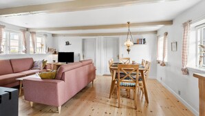 Una sala de estar con un sofá rosa, una mesa de comedor con sillas y un televisor.