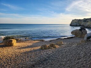 A beach with clear blue water, sandy shore, and rocky formations. - CASA ROGEL: PRIVATE HEATED POOL, GAMES, WIFI, WALK TO TOWN, 5 MIN DRIVE TO BEACH (Alcantarilha)