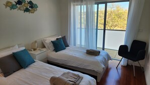 Une chambre d’hôtel avec deux lits, une table de chevet, une chaise et une vue sur l’extérieur.