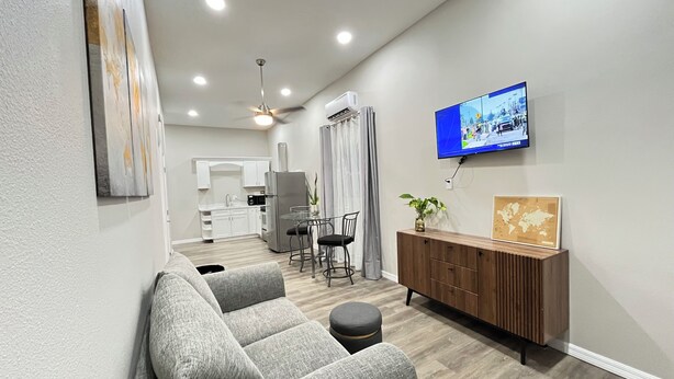 A modern living room with a grey sofa, a wooden cabinet, and a television mounted on the wall.
