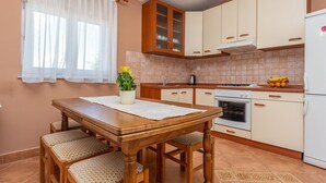 A kitchen with a wooden table, chairs, a stove, and a refrigerator. - 2 bedroom cozy apartment in Sveti Filip i Jakov (Sveti Filip i Jakov)