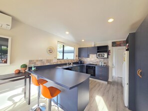 A modern kitchen with a central island, bar stools, a microwave, and a refrigerator.