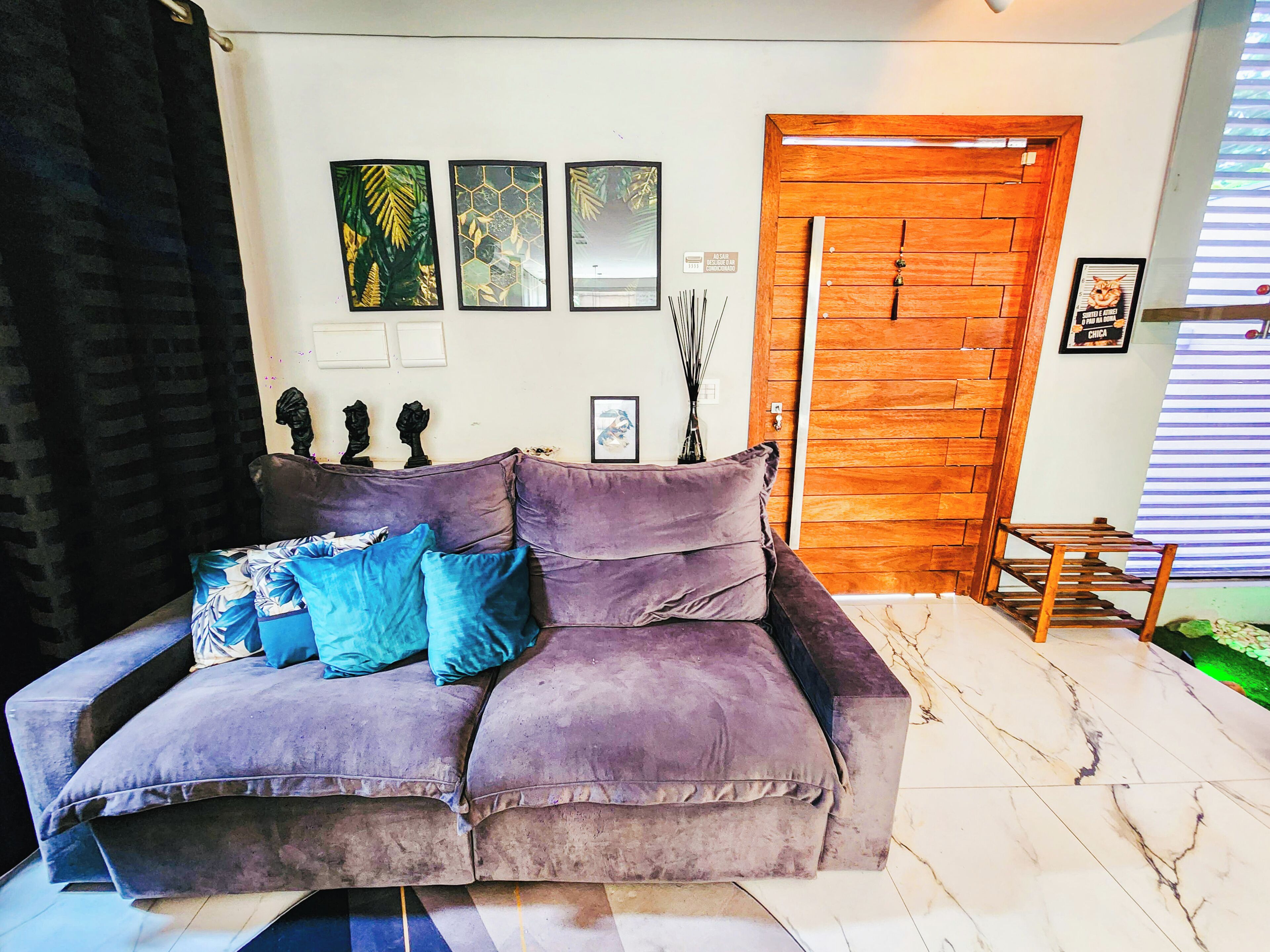 A purple sofa with blue cushions, a wooden door, and wall art.
