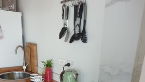 A kitchen with a wooden countertop, a built-in stove, a sink, and a hanging pot rack. - Million Dollar View! (Auckland)