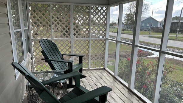 Une véranda couverte avec un plancher en bois et un treillis décoratif.